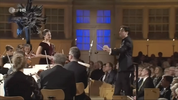 2017_Regula_Muehlmann_singt_vor_grossem_Orchester_Mikro_in_ca_1m_Pfeil.png